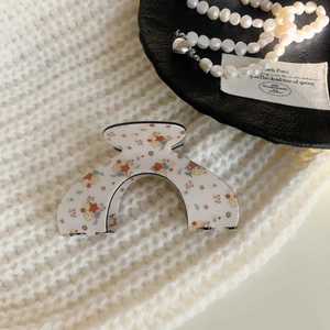 Chic cream acrylic hair claw clip with vintage floral pattern on soft knit background