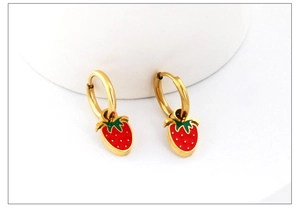 Close-up of strawberry earrings with red pendants and green leaves on golden hoops