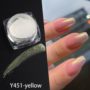 Macro shot of yellow aurora pearl nail powder in jar with golden shimmer finish on nails