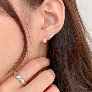Close-up of S925 sterling silver drop earrings and quilted band ring on a model