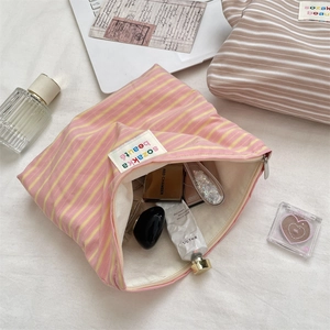 Close-up of a striped makeup bag with colorful logo patch and interior cosmetic items
