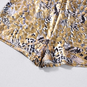Close-up of golden metallic animal print fabric and precise hem stitching on summer shorts