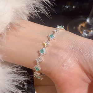 Macro shot of silver bracelet with emerald-cut green stones and sparkling zircons