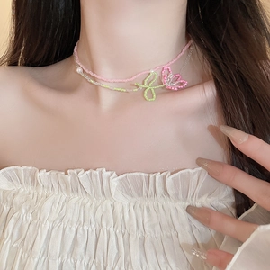 Detail of pink and green beaded necklace with floral charm and white imitation pearl
