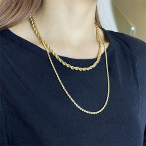 Detalle de cadenas de cuerda doradas dobles que muestran textura de metal en camisa negra