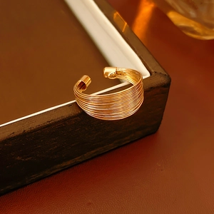 Makroaufnahme eines minimalistischen goldenen Mehrschichtrings auf einem Holztablett
