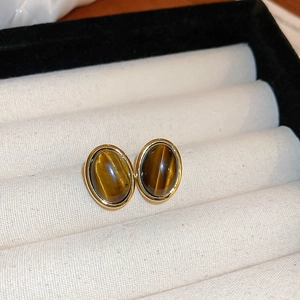 Close-up of vintage oval tiger eye stud earrings with gold trim in a white velvet box