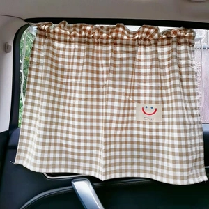 Close-up of beige plaid baby car sunshade with breathable cotton texture and smiley label