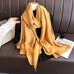 Close-up of a premium golden satin scarf on a leather sofa with fashion accessories