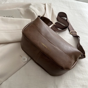 Borsa a tracolla retrò in pelle marrone scuro con tracolla jacquard su sfondo blazer beige