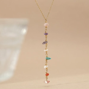 Elegant gold chain necklace with colorful boho natural stone pendant on beige background