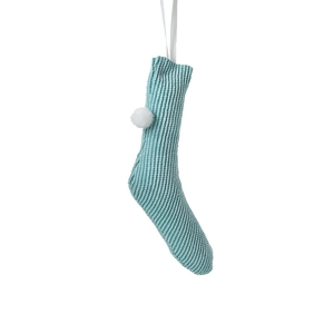Light teal knitted Christmas stocking with white pom-poms and hanging loop on white background