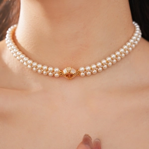 Détail du collier de perles à double rang avec fermoir doré et pierre précieuse orange