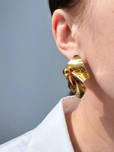 Close-up of golden metallic irregular wrinkled texture earrings on a female model
