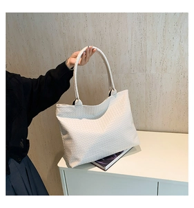Close-up of the woven texture on a large cream white tote bag in a minimalist setting