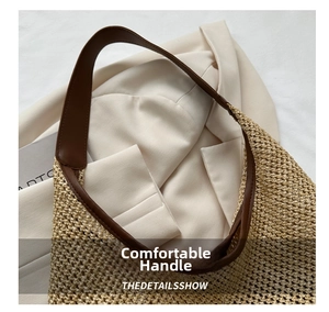 Detail view of woven straw tote bag featuring brown leather handle and fine stitching