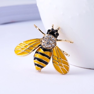 Elegant gold bee brooch with yellow enamel and white crystals on white background