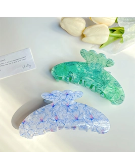 Close-up of floral and leaf print hair claws in green and blue on white background