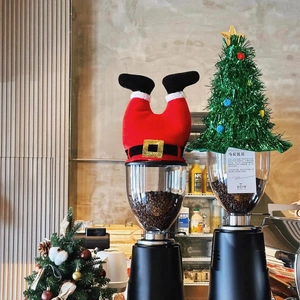 Creative Christmas set with red Santa legs and green tree hat decor on a coffee machine