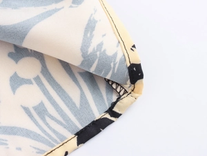Close-up of fine stitching and double-needle seams on the beige printed shirt dress