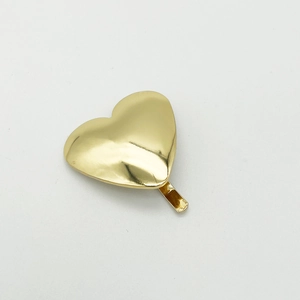 Detail shot of a minimalist gold heart-shaped metal hair clip with a polished finish