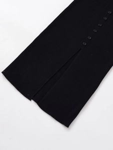 Detail view of black ribbed knit midi dress featuring decorative buttons and side slit