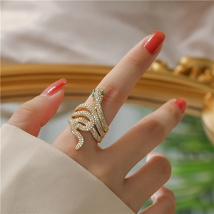 Detailed view of an 18K gold plated snake ring encrusted with white and green zircons