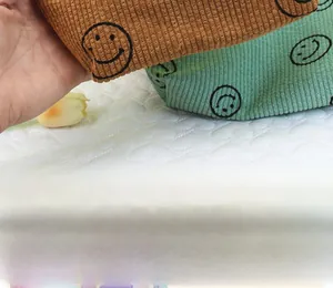 Detailed texture of corduroy toiletry bags with embroidered smileys in brown and green