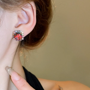 Macro shot of elegant red crystal stud earrings with a halo of small rhinestones on a model