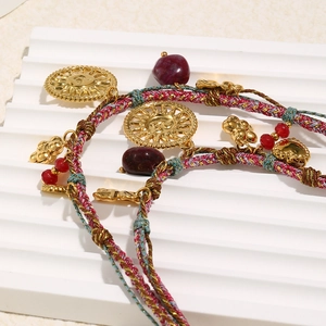 Detail view of 18K gold plated sun pendant with red bead on braided cord necklace