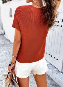 Back view of orange short sleeve knit top paired with white denim shorts and woven bag