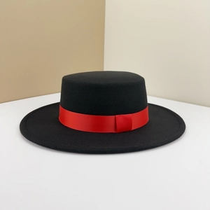Detailed view of black flat top boater hat featuring a vibrant red grosgrain ribbon
