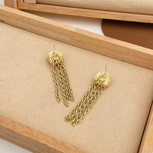 Detail of gold fringe earrings with twisted chain tassels in a jewelry display box