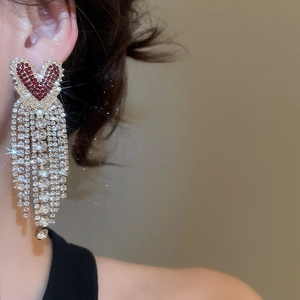 Detailed view of long tassel earrings with red heart and sparkling rhinestones