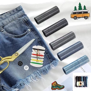 Close-up of denim iron-on repair kit with blue fabric patches, sewing threads, and accessories