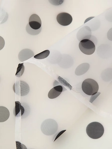 Detail of white semi-transparent organza fabric with classic black polka dot pattern
