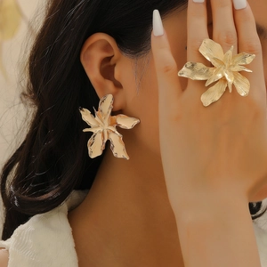 Exaggerated golden floral jewelry set featuring a bold ring and statement earrings on model