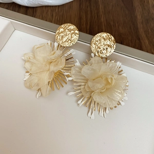 Detail of champagne chiffon flower earrings with textured gold studs and radial spike accents