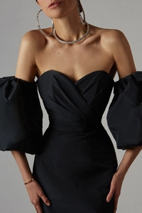 Detail of elegant black off-shoulder dress with V-neck pleats and dramatic lantern sleeves