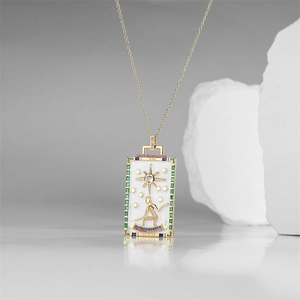 Macro detail of gold tarot THE STAR pendant necklace with green and blue cubic zirconia