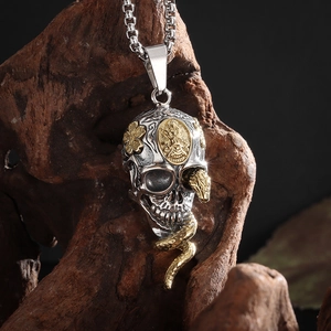 Detail of silver skull pendant with golden snake wrap and flower relief on wood