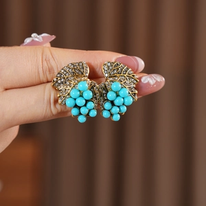 Detail of vintage gold leaf earrings with blue beads and crystals in a grape cluster design