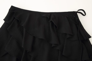 Detail of black tiered ruffle mini skirt with drawstring side tie on crepe fabric