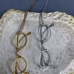 Minimalist metallic eye pendant necklaces in gold and silver finish on ceramic tray