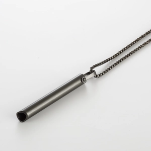 Macro detail of dark grey stainless steel cylindrical breathing meditation pendant