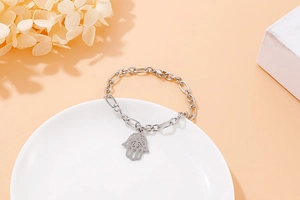 Detail view of silver Hamsa Hand pendant on a Figaro chain bracelet with lobster clasp