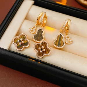 Macro detail of gold flower earrings and pendants with tiger eye stone and small pearls