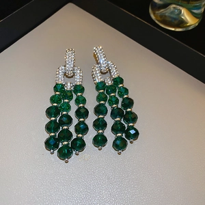 Vue détaillée de boucles d'oreilles pompons avec strass brillants et perles vertes
