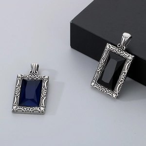 Détail de pendentifs carrés vintage avec pierres bleues et noires et gravures florales