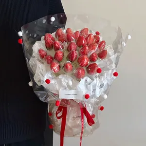 Handheld strawberry bouquet with snowflake pattern cellophane and festive red ribbon bow